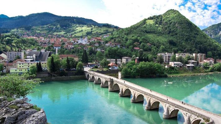 a bridge over a river with a city and mountains at Viola i Detelina Apartments in Perućac