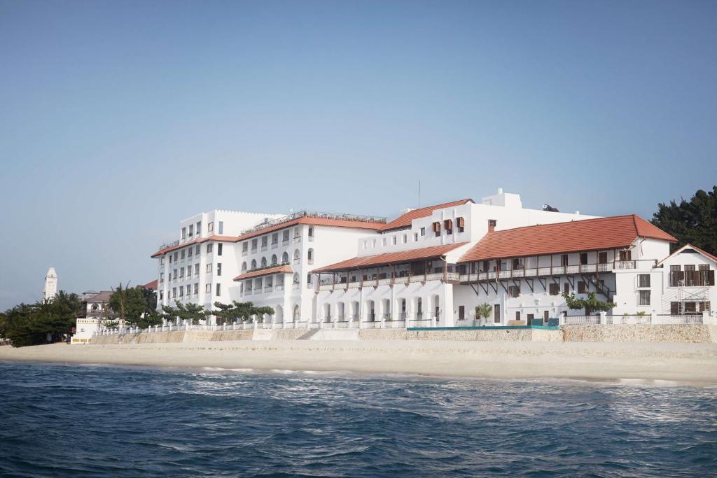 a large white building on a beach next to the water at Park Hyatt Zanzibar in Zanzibar City