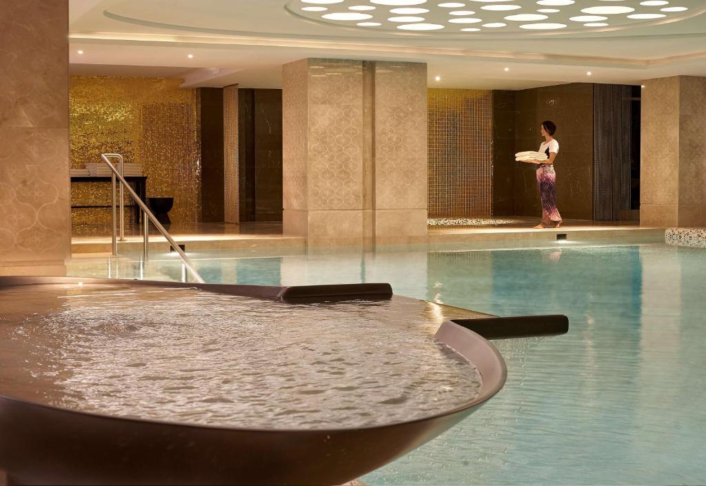 una mujer parada junto a una piscina en un edificio en Hyatt Regency Istanbul Atakoy, en Estambul