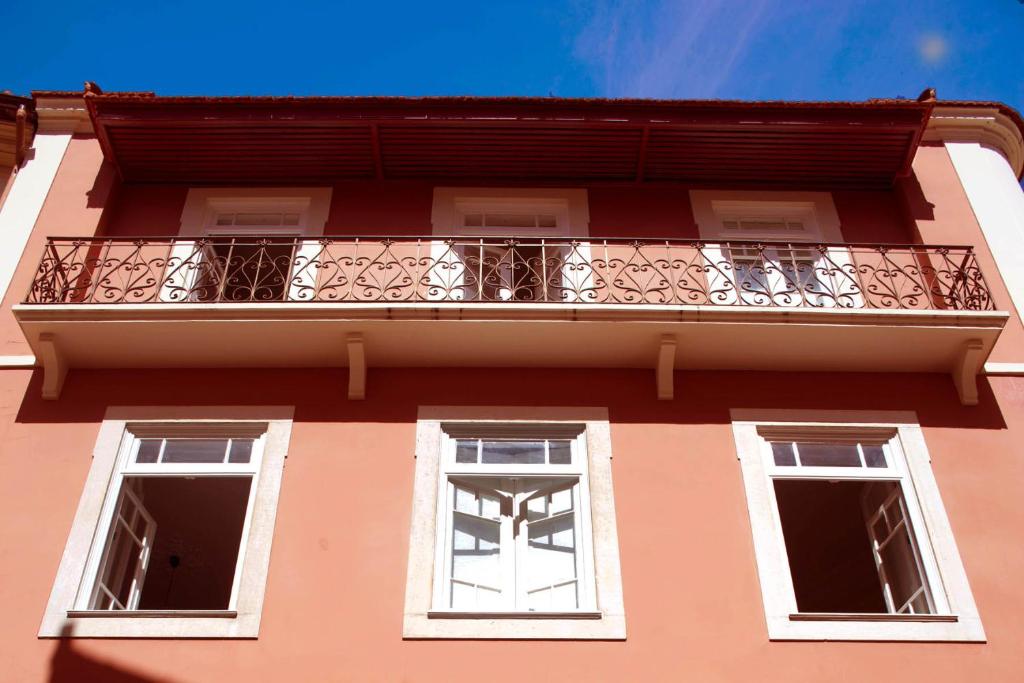 a building with a balcony and two windows at cinco em 5 in Coimbra