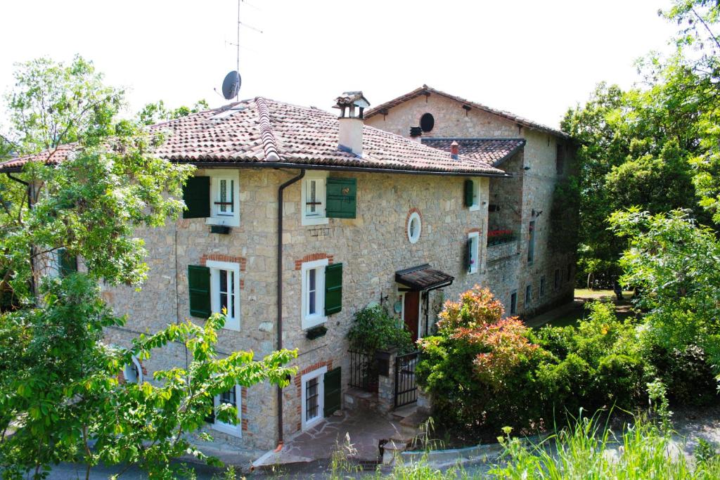 una vieja casa de piedra con árboles delante de ella en La Quercia - la maison des arts, en Vezzano sul Crostolo