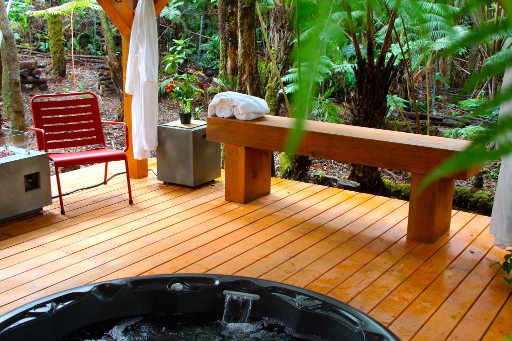 a wooden deck with a bench and a chair at At the Craters Edge in Volcano