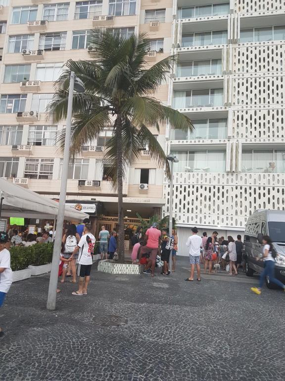 a group of people standing around a street with a palm tree at Apartamento Copacabana in Rio de Janeiro