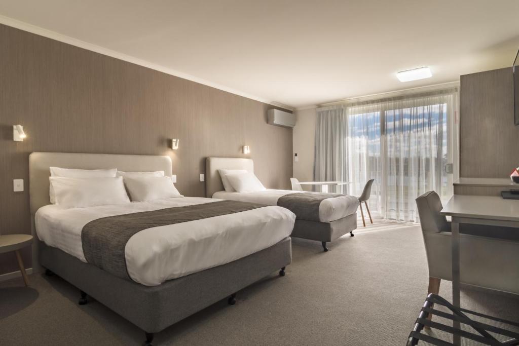 a hotel room with two beds and a desk at Argosy Motor Inn in Devonport