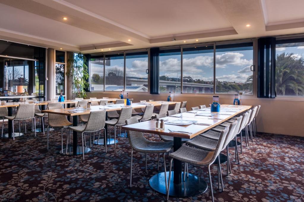 a row of tables and chairs in a room with windows at Argosy Motor Inn in Devonport