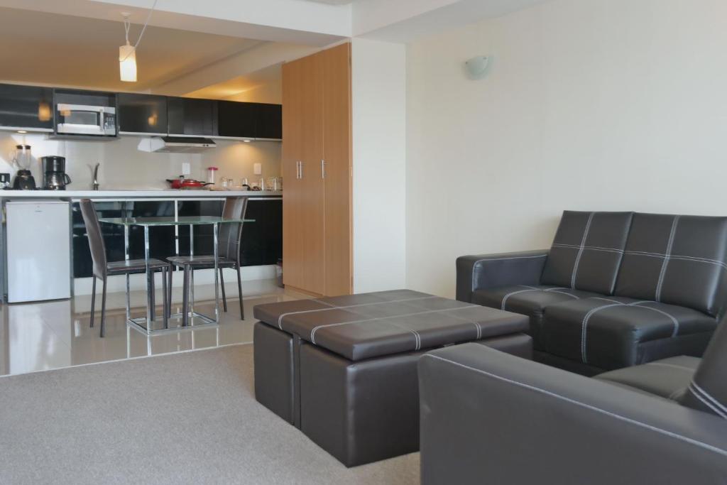 An open-plan suite pairs a black leather lounge with a compact kitchen and breakfast bar.