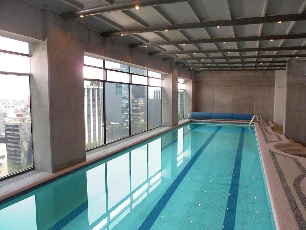 a large swimming pool in a building with windows at Capri Reforma 410 in Mexico City