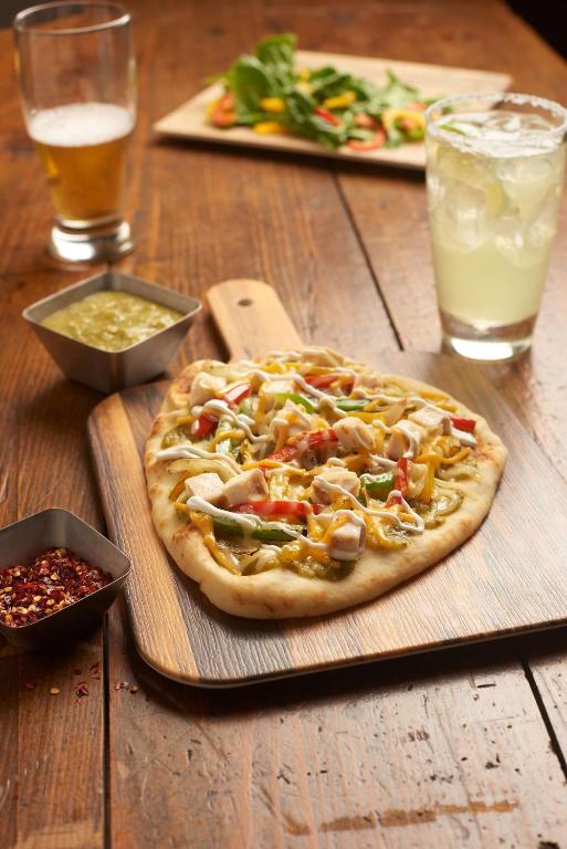 a pizza sitting on top of a wooden table at Hyatt Place Austin Airport in Austin