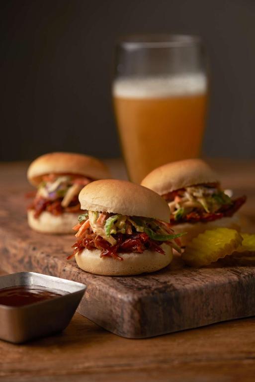 three sandwiches on a cutting board with a glass of beer at Hyatt Place Austin Airport in Austin