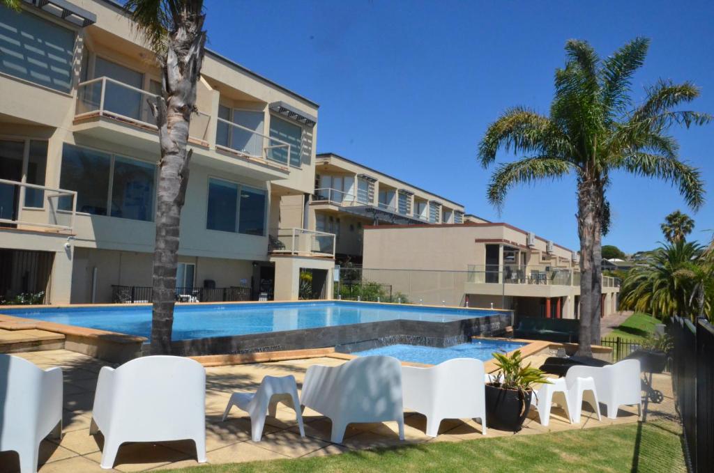 
a patio area with chairs, tables and umbrellas at The Bluff Resort Apartments in Victor Harbor
