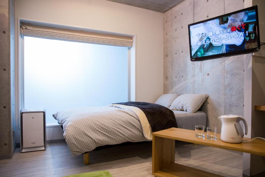 1 dormitorio con 1 cama y TV en la pared en bmj Shinjuku Okubo en Tokio