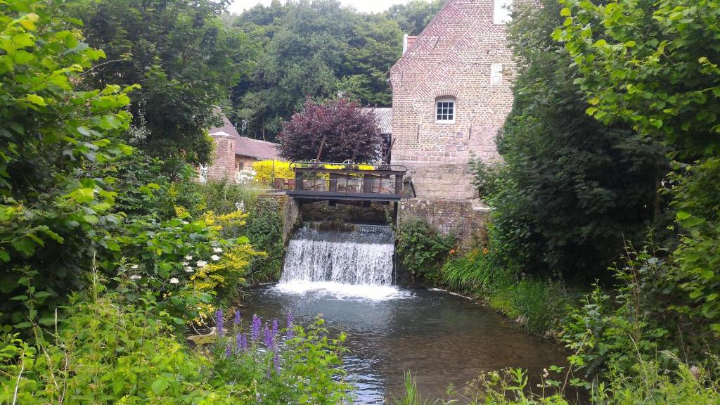 un pont sur une rivière avec une cascade dans l'établissement Le moulin de Cohem, à Blaringhem