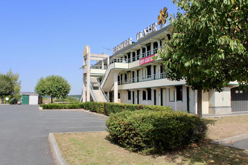 Un grand bâtiment blanc avec un escalier se trouve devant. dans l'établissement Première Classe Chateauroux - Saint Maur, à Saint-Maur