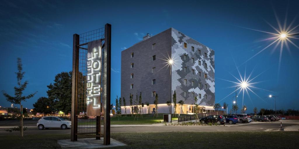 un grand bâtiment avec un panneau devant lui dans l'établissement Hotel The Cube, à Fidenza