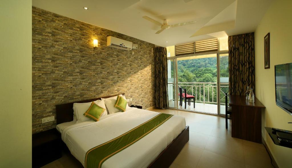 a hotel room with a bed and a balcony at Rivulet Resort in Munnar