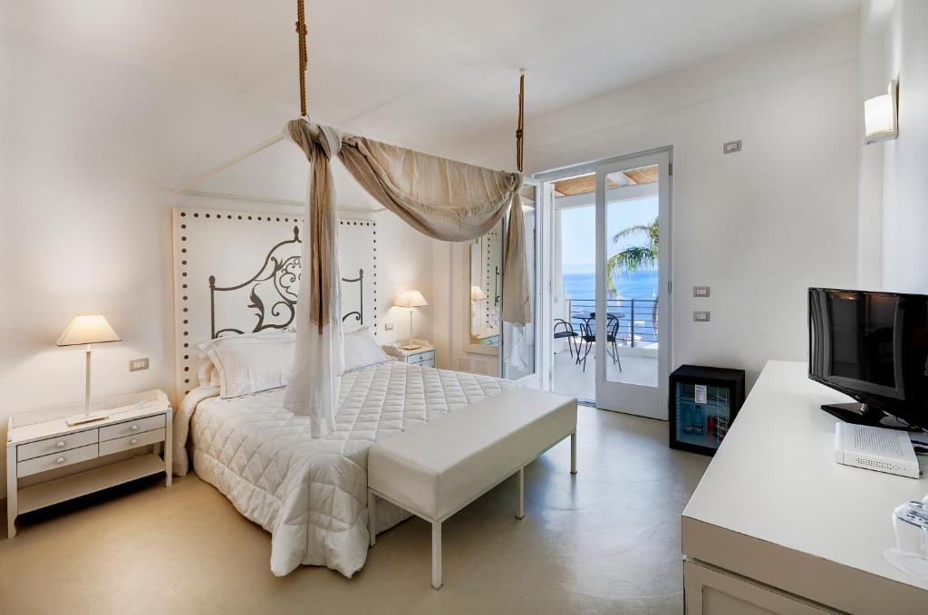 Hotel Villa Enrica - Aeolian Charme في ليباري: غرفة نوم بيضاء مع سرير مظلة وتلفزيون