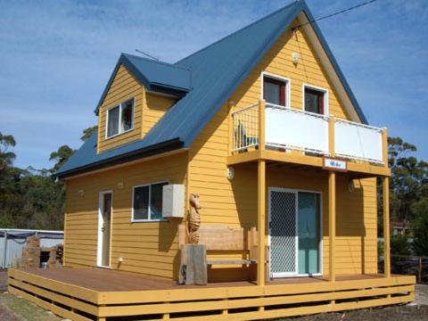 a small yellow house with a blue roof at Beachs 'n Greens in Greens Beach