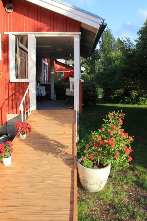 a porch of a red house with two pots of flowers at Wanha Autti Camping in Autti