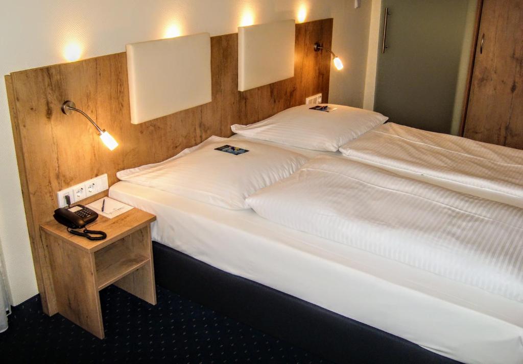 a bedroom with a large bed with a wooden headboard at Hotel Daniel in Munich