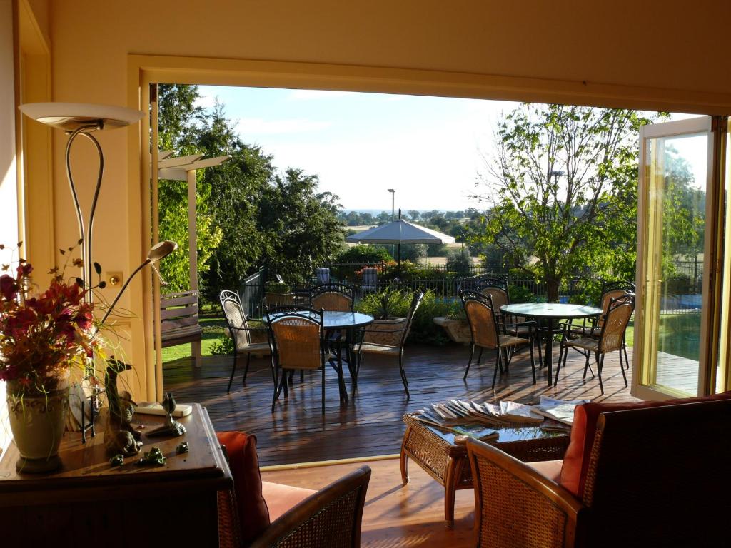 un patio con mesas y sillas y una gran puerta corredera de cristal en Pericoe Retreat en Dubbo