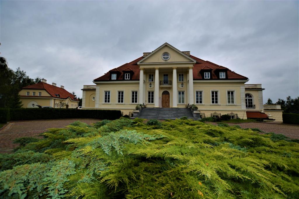 una grande casa bianca con un orologio sopra di Dwor Osieczek a Pniewy