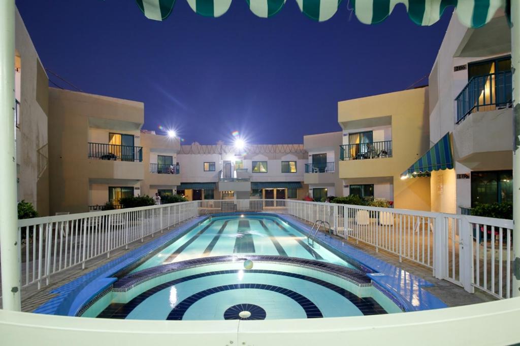 a swimming pool in front of a building at night at Summer Land Hotel Apartment in Sharjah