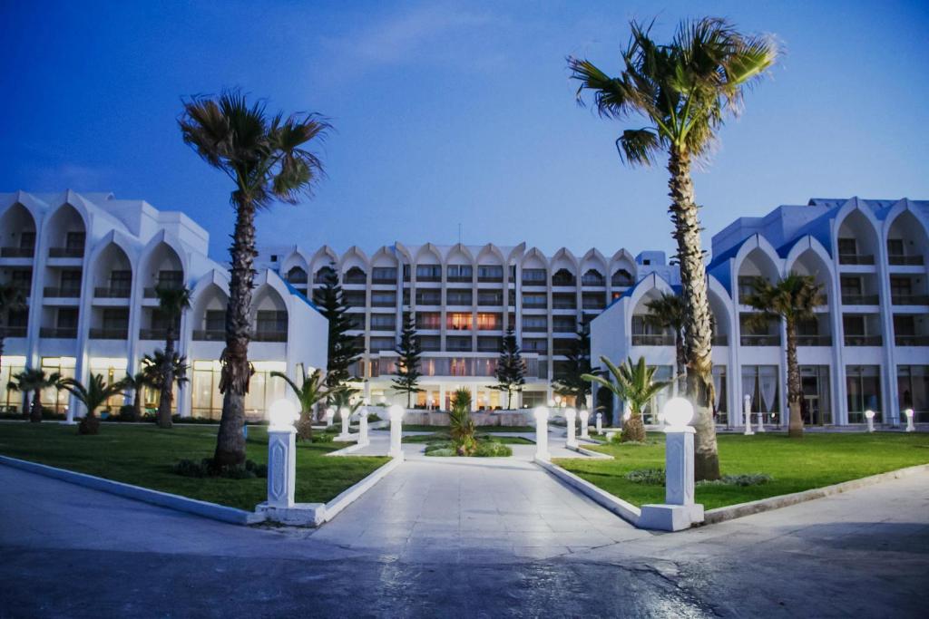 a large building with palm trees in front of it at Amir Palace in Monastir