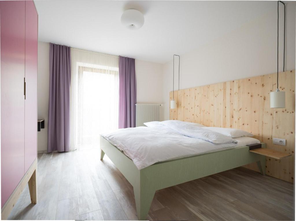 a bedroom with a bed and a large window at Residence Vis à Vis in Rasùn di Sotto