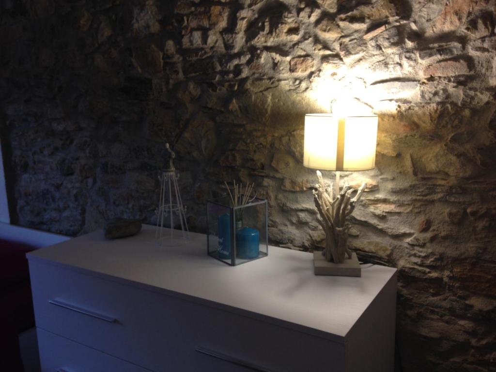 a lamp on a dresser in a room with a stone wall at Borgo house in Arcola