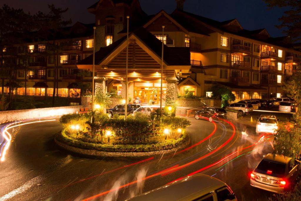 a building with cars driving down a street at night at PRIVATE unit CAMP JOHN HAY MANOR in Baguio