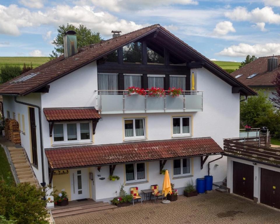 een wit huis met een balkon met rood dak bij Gästehaus Beranek in Marktoberdorf