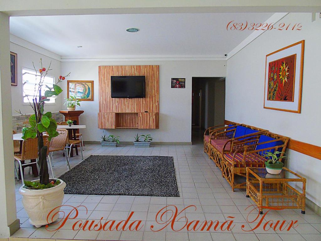 a living room with a couch and a tv on a wall at Pousada Xamã Tour in João Pessoa