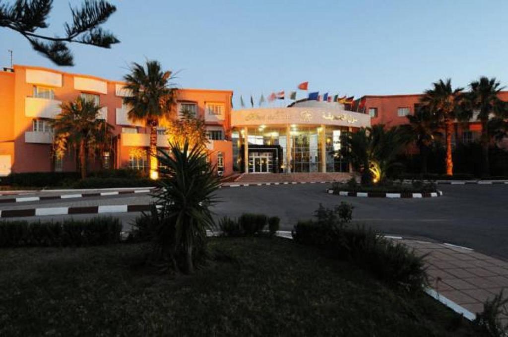 ein Gebäude mit einem Parkplatz davor in der Unterkunft Hotel du Parc in Tunis