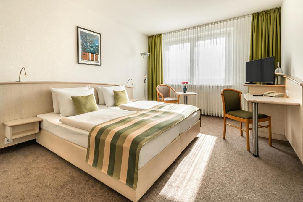 a hotel room with a large bed and a desk at Panorama Inn Hotel in Hamburg
