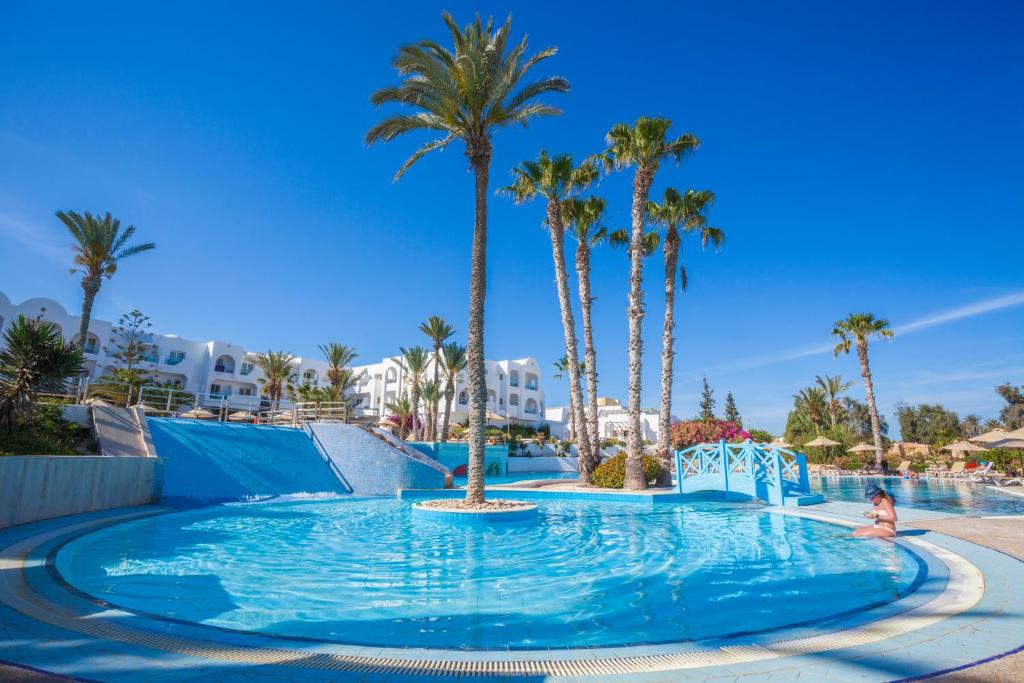 een kind in een zwembad in een resort met palmbomen bij Seabel Aladin Djerba in Aghīr