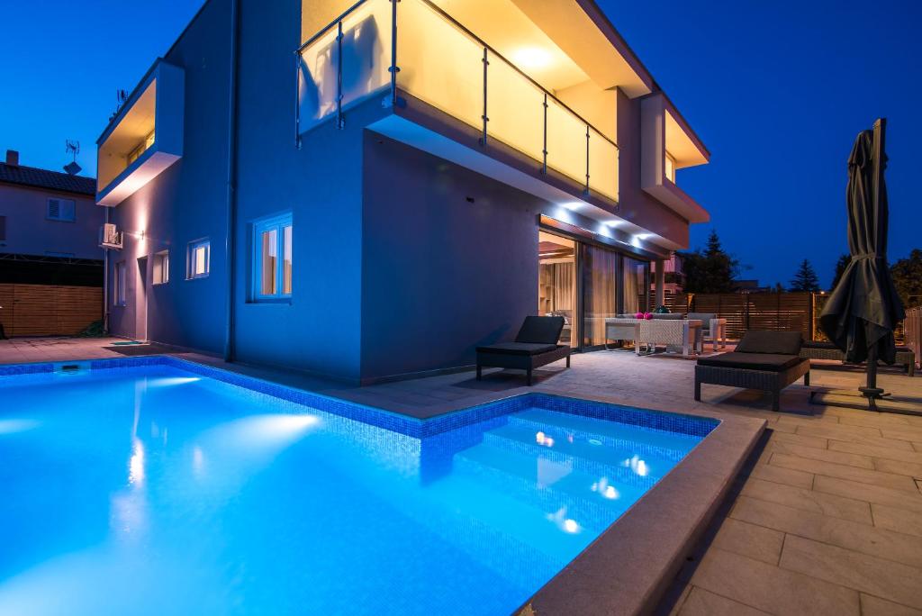 a swimming pool in front of a house at night at Luxury Apartment Imperia in Krk