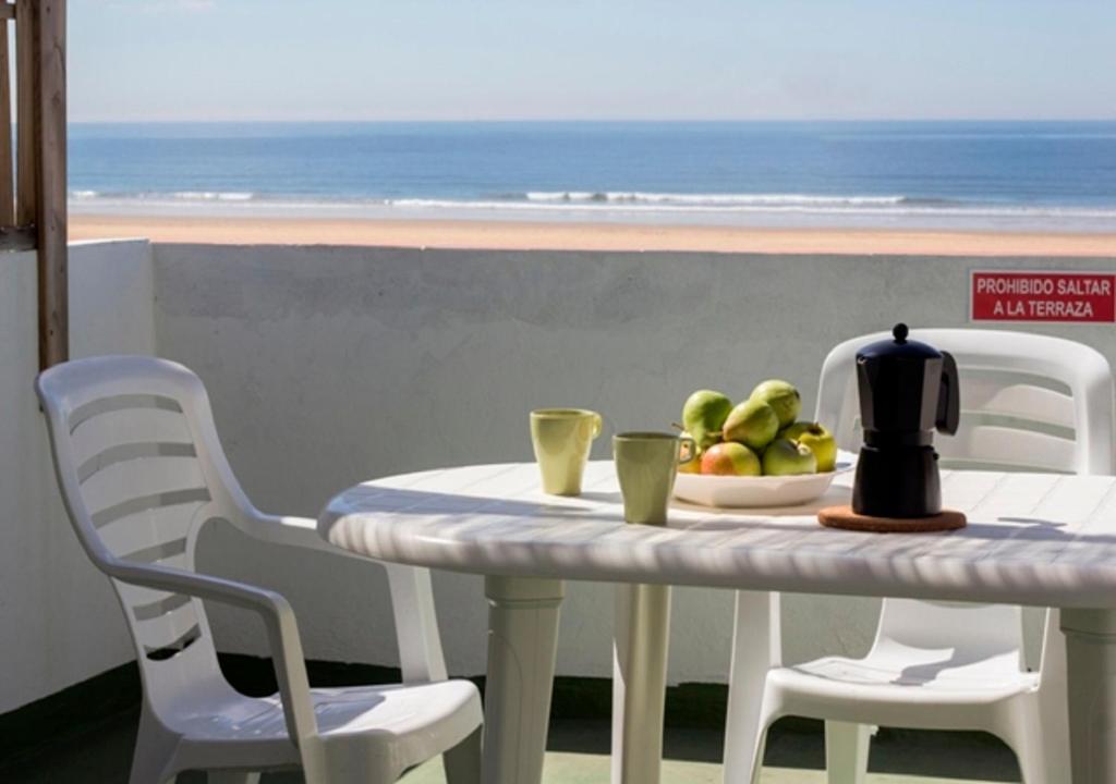 a table with a bowl of fruit on it with a view of the ocean at Apartamentos Calypso in Punta Umbría