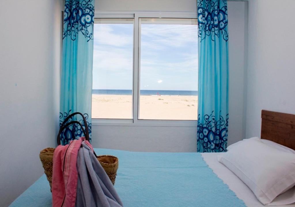 a bedroom with a bed and a window with a beach at Apartamentos Calypso in Punta Umbría
