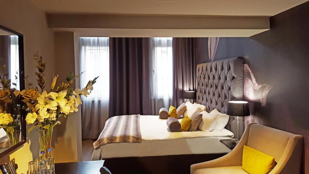a hotel room with a bed and a chair and flowers at Grey Street Hotel in Newcastle upon Tyne