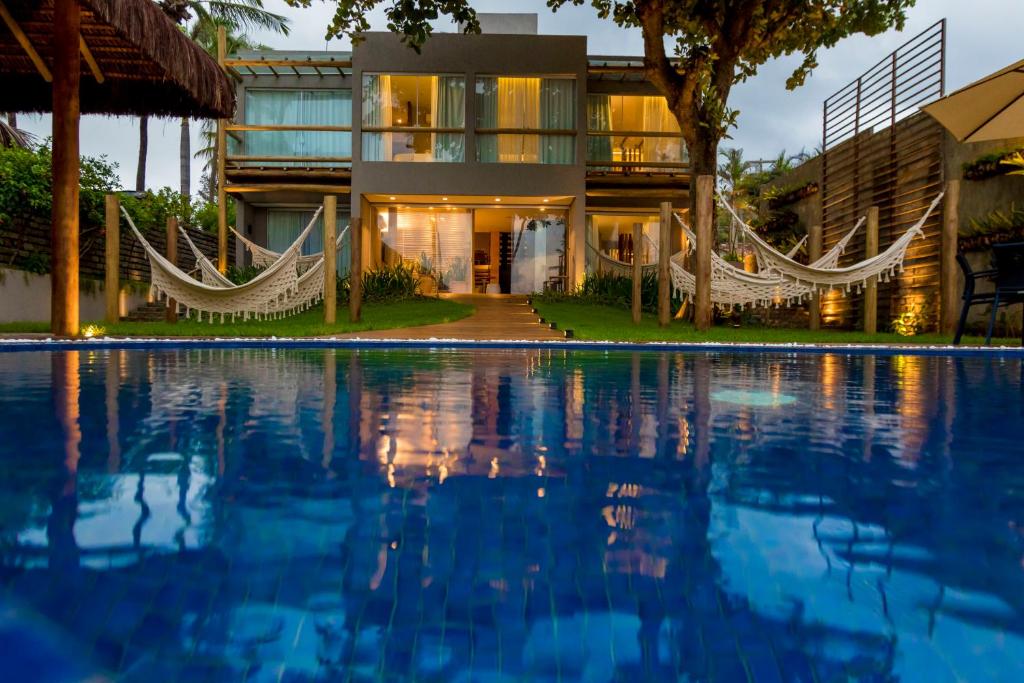 a house with a swimming pool and hammocks in front of it at Flor de Lis Exclusive Hotel in Maceió