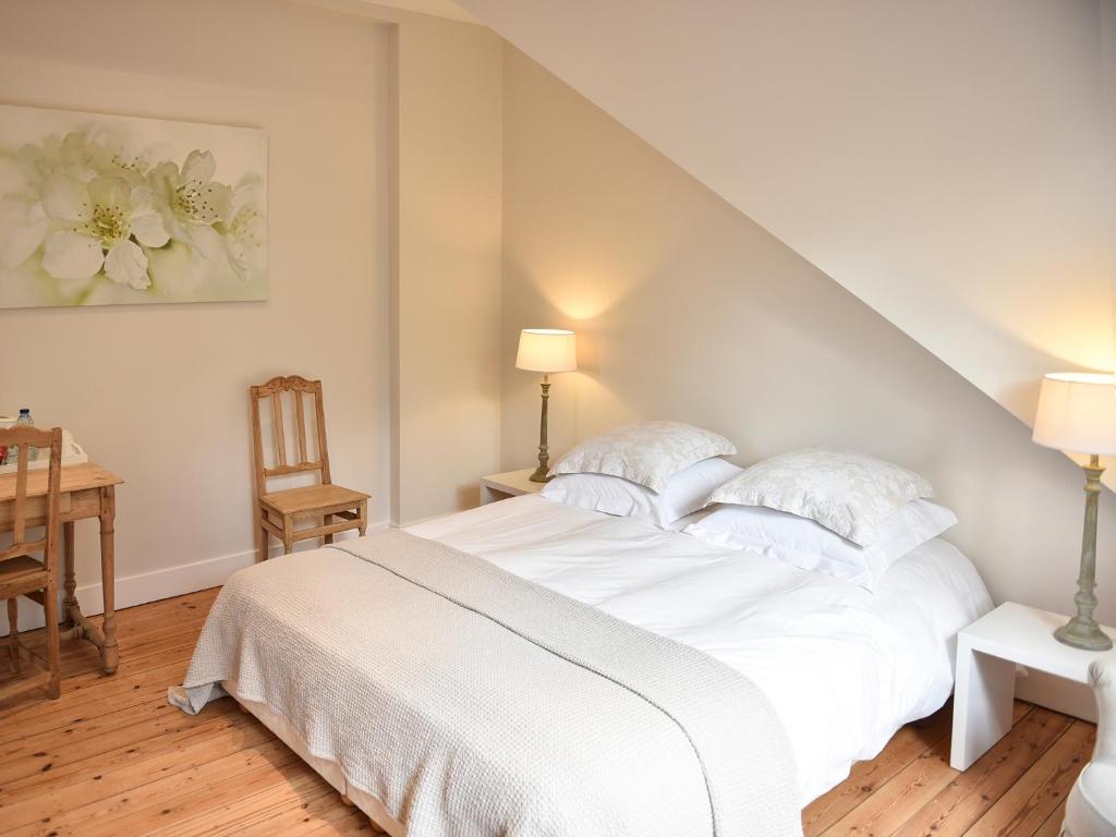 a white bedroom with a white bed and a table at B&B Salve in Brussels