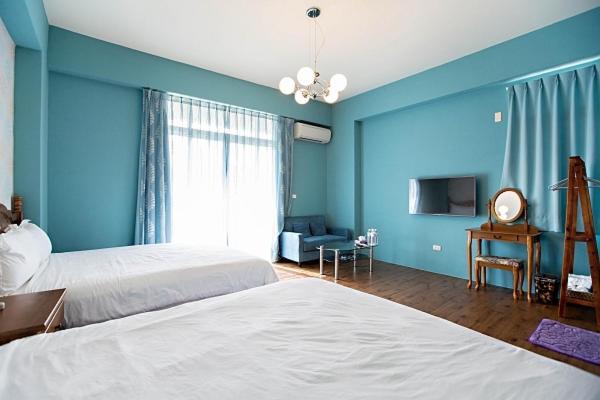 a bedroom with two beds and a blue wall at Slowly B&amp;B in Taitung City