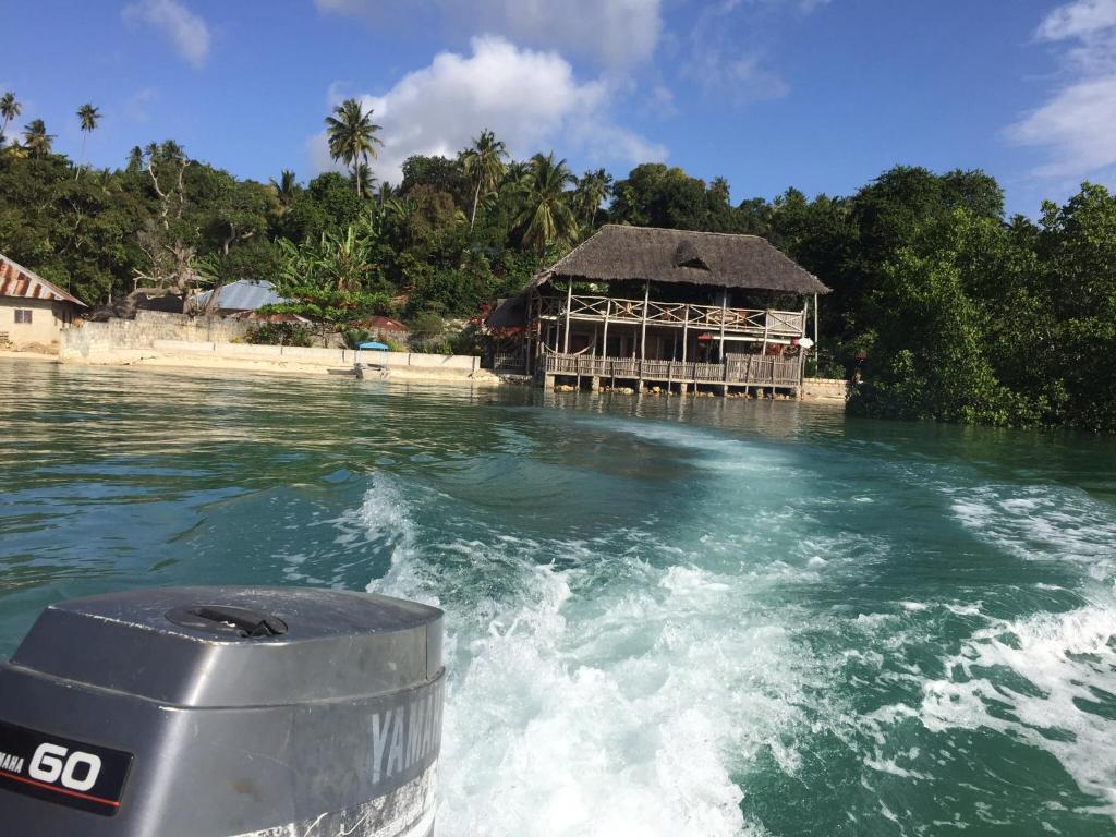 a boat in the water with a building on the shore at Lala lodge Pemba Zanzibar in Mgini