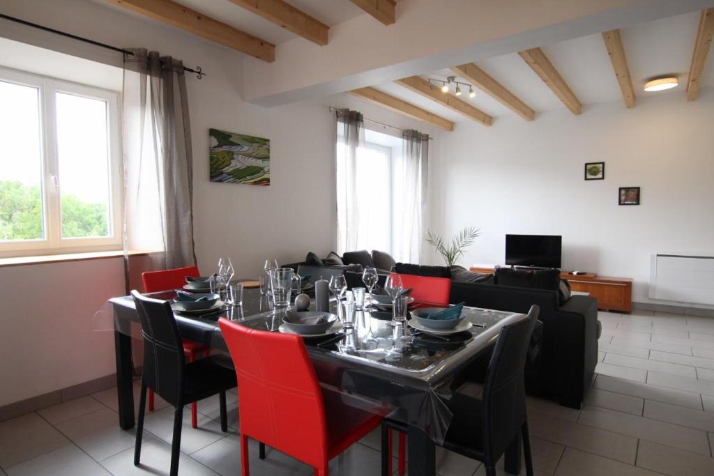 jadalnia ze stołem i czerwonymi krzesłami w obiekcie Gite du lavoir w mieście Le Puy-en-Velay