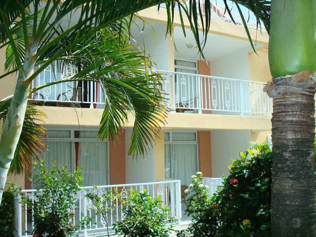 a building with a balcony and a palm tree at Residence Le Royaume du Soleil in Sainte-Anne