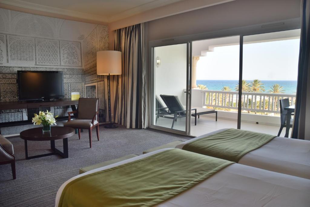 a hotel room with a bed and a view of the ocean at OCEANA Hotel & Spa in Hammamet