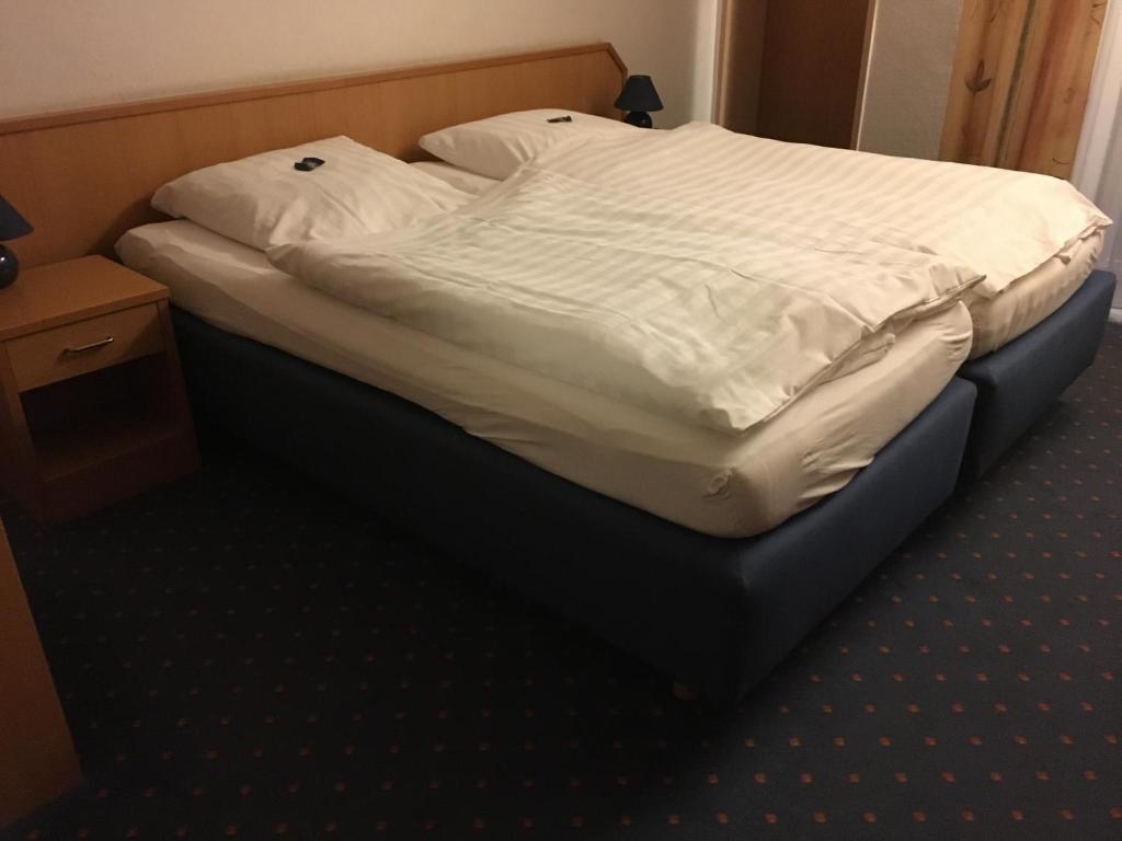 un letto con lenzuola bianche e cuscini sopra di Landhotel Kussmann a Wrexen