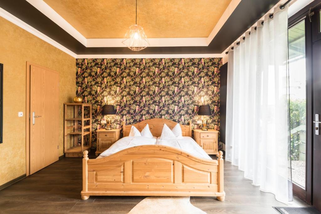 um quarto com uma cama de madeira e papel de parede floral em Engel Hotel Grill Bar em Niedernhausen