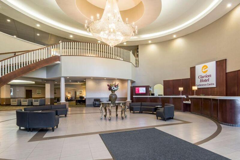 a lobby with a table and chairs and a chandelier at Clarion Hotel & Conference Center Sherwood Park in Sherwood Park
