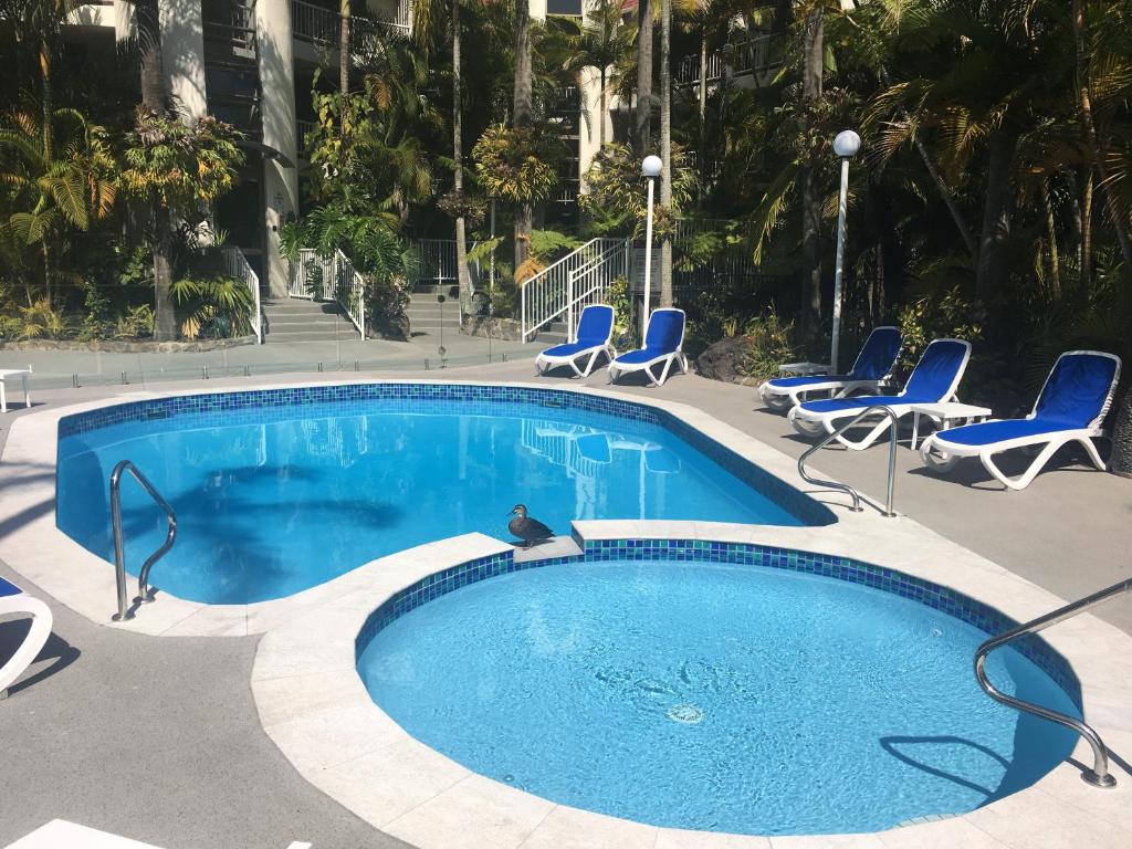 una piscina con sillas azules y una piscina en Copacabana Apartments, en Gold Coast